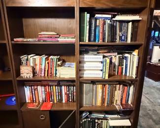 Large dark wood bookcase unit filled with a diverse collection of hardcover and paperback books.