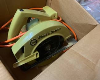 Vintage Black & Decker avocado green corded circular saw resting inside a cardboard storage box.
