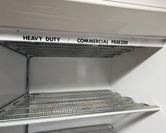 Interior view of an upright heavy-duty commercial freezer featuring multiple metal wire shelves.