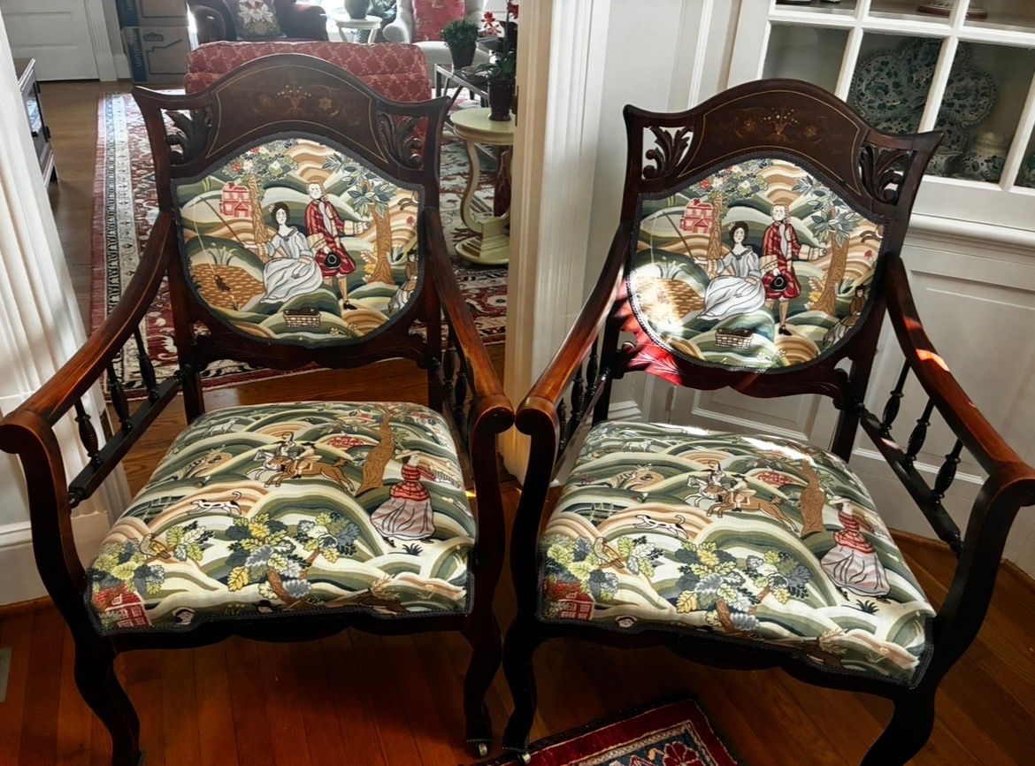 Beautiful matching wooden armchairs featuring decorative inlay, carved details, curved arms, and colorful scenic upholstery.