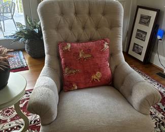 Elegant beige upholstered armchair with a tall tufted back and timeless traditional styling. Neutral, versatile, and easy to incorporate into almost any room.