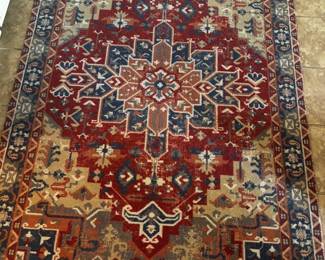 Decorative area rug featuring an intricate geometric medallion pattern in rich red, navy blue, ivory, and muted earth tones.