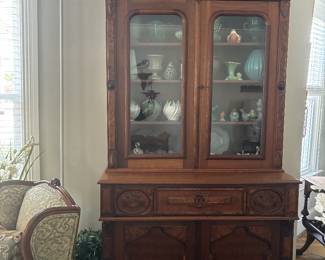 Tall carved glazed secretary bookcase with fitted writing drawer, interior compartments, and green writing surface. Ornate architectural details throughout.