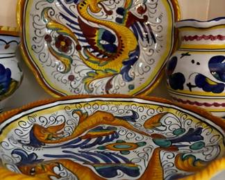 Decorative Italian ceramic serving pieces featuring vibrant blue, yellow, green, and burgundy floral and bird motifs.