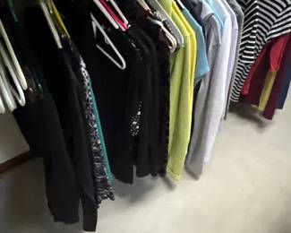 election of women's long-sleeve tops and t-shirts, including striped, solid, and patterned styles, hanging on plastic clothes hangers.