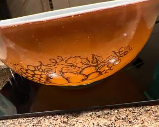 Vintage Pyrex Cinderella mixing bowl in the Autumn Harvest pattern, featuring a burnt orange gradient background with brown fruit illustrations.