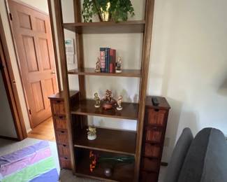 Tall vintage wooden shelving unit with open central display shelves flanked by side columns featuring small storage drawers.