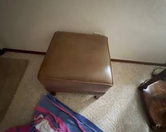 Mid-century leather ottoman with nailhead trim and short wooden feet.