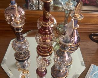 Collection of Egyptian-style mouth-blown glass perfume bottles with gilded accents displayed on an octagonal mirrored vanity tray.