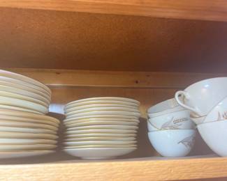 Lenox collection of mid-century fine china dinnerware with gold rims and wheat stalk motifs, including stacked plates, saucers, and cups.