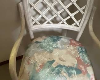Vintage whitewashed rattan armchair featuring a trellis-style arched back and a floral upholstered seat cushion.