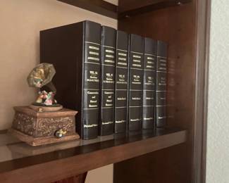 Collection of bound Michigan Statutes Annotated law books displayed on a wooden shelf alongside a miniature decorative gramophone music box.