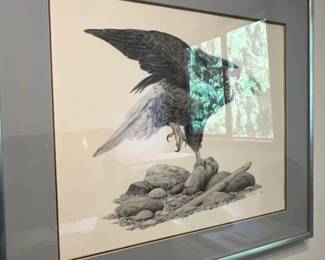 Framed wildlife art print depicting a predatory bird perched on rocks with outstretched wings, housed in a double-matted silver metal frame under glass.