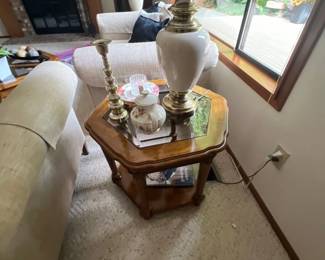Hexagonal wood side table featuring a mirror inset top, decorated with a brass table lamp, candlestick holder, and porcelain accents.
