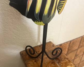 Hand-painted wooden fish sculpture mounted on a black wrought iron stand with scroll feet.
