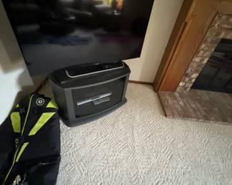 Large Sony flat-screen television resting on a dark gray media cabinet next to a black and neon yellow sports bag.