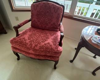 French Provincial style armchair featuring a carved dark wood frame, padded armrests, and plush pink damask fabric upholstery.