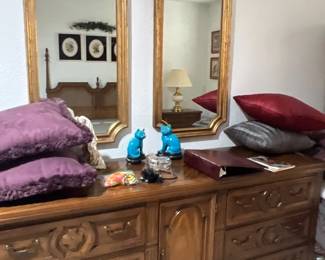 Vintage Spanish revival style wooden dresser with matching tall gilt-framed wall mirrors, paired with turquoise cat figurines and decorative throw pillows.