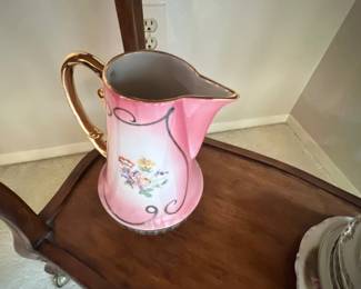 Vintage pink porcelain pitcher featuring hand-painted floral motifs and a gilt handle and trim
