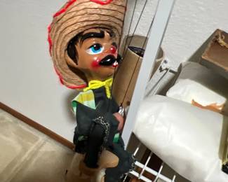 Vintage Mexican marionette string puppet wearing a straw sombrero, yellow neckerchief, and black charro outfit.