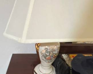 Vintage porcelain table lamp featuring a classic courtyard vignette with gold accents and a large cream fabric shade.