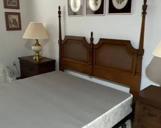 Traditional wooden four-poster bed frame featuring woven cane inserts in the headboard, flanked by matching dark wood nightstands.
