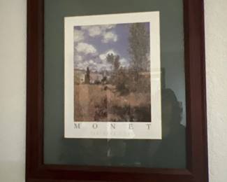 Framed Claude Monet exhibition poster featuring an impressionist landscape scene, housed in a dark wooden frame with double matting.