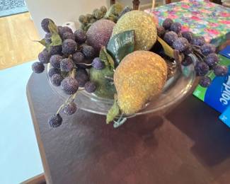 A clear glass pedestal centerpiece bowl filled with beaded, sugared decorative artificial fruit including pears, apples, and grapes.