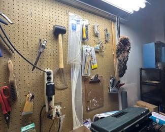 Workshop area featuring pegboard-mounted hand tools, zip ties, power strips, and a plastic toolbox on the workbench.
