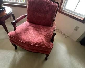 French Provincial style armchair featuring a carved dark wood frame, padded armrests, and plush pink damask fabric upholstery.