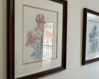 Framed floral watercolor prints in dark wood frames, featuring pastel iris blooms under glass.