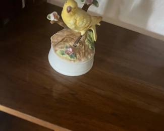 Vintage ceramic yellow bird music box featuring a songbird perched on a flowering branch base.