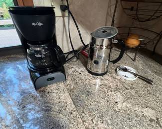 Black Mr. Coffee 4-cup drip coffee maker alongside a stainless steel electric milk frother on a granite countertop.