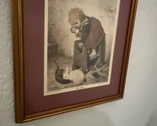 Framed art print depicting a child standing on a stool looking down at a rabbit eating from a bowl, set within a burgundy mat and gold-toned wooden frame.