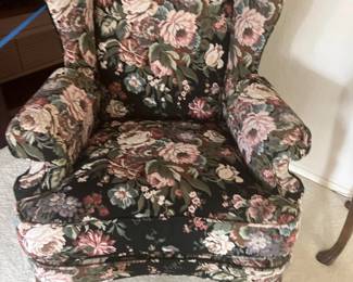Traditional wingback armchair upholstered in a dark floral tapestry fabric, supported by wooden cabriole legs.