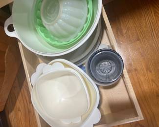 Collection of vintage Tupperware plastic kitchenware, including a Jel-Ring mold and serving bowls, stored inside a wooden drawer.