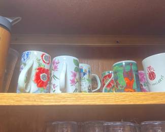 Collection of clear plastic highball tumblers and cut glass drinking glasses stored upside down on a wooden shelf.