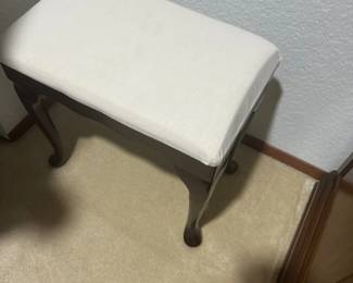 Traditional vanity stool or piano bench featuring a dark wood frame with cabriole legs and a cream-colored upholstered seat.