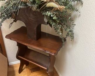 Vintage dark stain wooden accent table with lower trough shelf, topped with a rustic decorative vessel holding a large dried botanical arrangement.