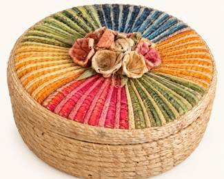Round Woven Basket with Lid ◆ Natural straw construction featuring colorful radial weaving in blue, green, orange, pink, and yellow, topped with decorative fabric rosettes.