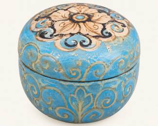 Round lidded trinket box featuring a turquoise-blue finish, ornate cream floral design, gold-tone scrollwork, and distressed detailing.