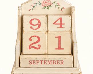 Wooden Perpetual Block Calendar ◆ Distressed cream-colored wooden calendar with interchangeable number and month blocks, pink floral detailing, and decorative tabletop stand.