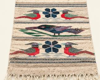 Rustic woven textile wall hanging featuring colorful birds, floral motifs, horizontal patterns, fringed edges, and wooden hanging rod.