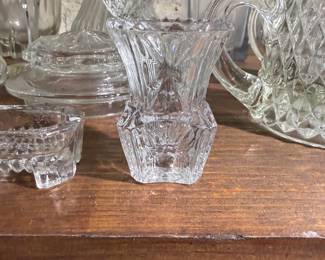 Pretty cut glass bud vase sitting among other pretty cut glass pieces.