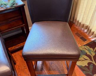 Four counter height bar stools with wooden legs and brown  leather seats and backs