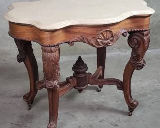 124 Lot 517 Antique carved walnut center table on casters with marble top
