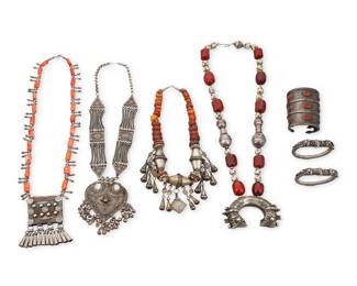 1213 A group of North African and Asian** style jewelry Comprising four necklaces including an Indian silver-toned metal necklace with a heart pendant and bell dangles (stamped N.K.; 26 x 5 in.), a North African-style coral and silvered metal bead necklace suspending a silvered metal box with cone dangles (30 1/2 x 4 1/4 in.), a graduated amber, red stone, and silvered metal bead necklace with incised bell and diamond-shaped dangles (22 x 3 3/8 in.), and a chunky necklace with red amber beads, trade beads, and silvered metal beads suspending a large crescent-shaped pendant with elaborate incised and stamped motifs (35 x 3 in.), as well as a likely Central Asian sterling silver tapered armband cuff with bezel-set orange glass lozenges, the top with gold-plated incised curvilinear motifs (6 1/4 inner C x 3 5/8 in.), and two East Asian sterling silver dragon bangles (each 7 in. inner C x 3/4 in.) 7 pieces  1358.6 grams gross Estimate: $300 - $500