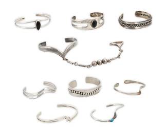1200 Nine Silver Cuff Bracelets Comprising two wide cuffs with silver wire or silver ball accents, two cuffs with set onyx, four narrow wave-form cuffs, one with set turquoise, and a Mexican sterling silver modernist style V-form cuff with attached matching ring on a chain Variously marked for maker: JEP [script] / GSkeets / NP; four marked for Mexico; seven marked for sterling 9 pieces  Largest 7 in. total inner C; Smallest 6 1/8 in. total inner C; ring size 8 1/2 in. 178.7 grams gross Estimate: $200 - $400