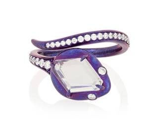 1029 Alexis NY: A Titanium, Colorless Sapphire and Diamond Ring Of a snake design featuring a portrait cut colorless sapphire accented by round diamonds, with maker's mark, 052632  Size: 7 1.9 grams gross Estimate: $1,800 - $2,200