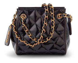 1221 CHANEL: A Vintage Small Black Patent Quilted Timeless Tote Circa 1996, Italy The small bag in quilted black patent leather and gold-tone hardware with zip top featuring Chanel branded logo leather luggage tag charm, two leather chain straps, and with black leather lining and two interior pockets Marked to interior: Chanel / Made in Italy; With interior Authenticity tag: 3826838  5 3/4 x 6 x 3 1/2 in., drop: 9 3/4 in. Estimate: $800 - $1,200